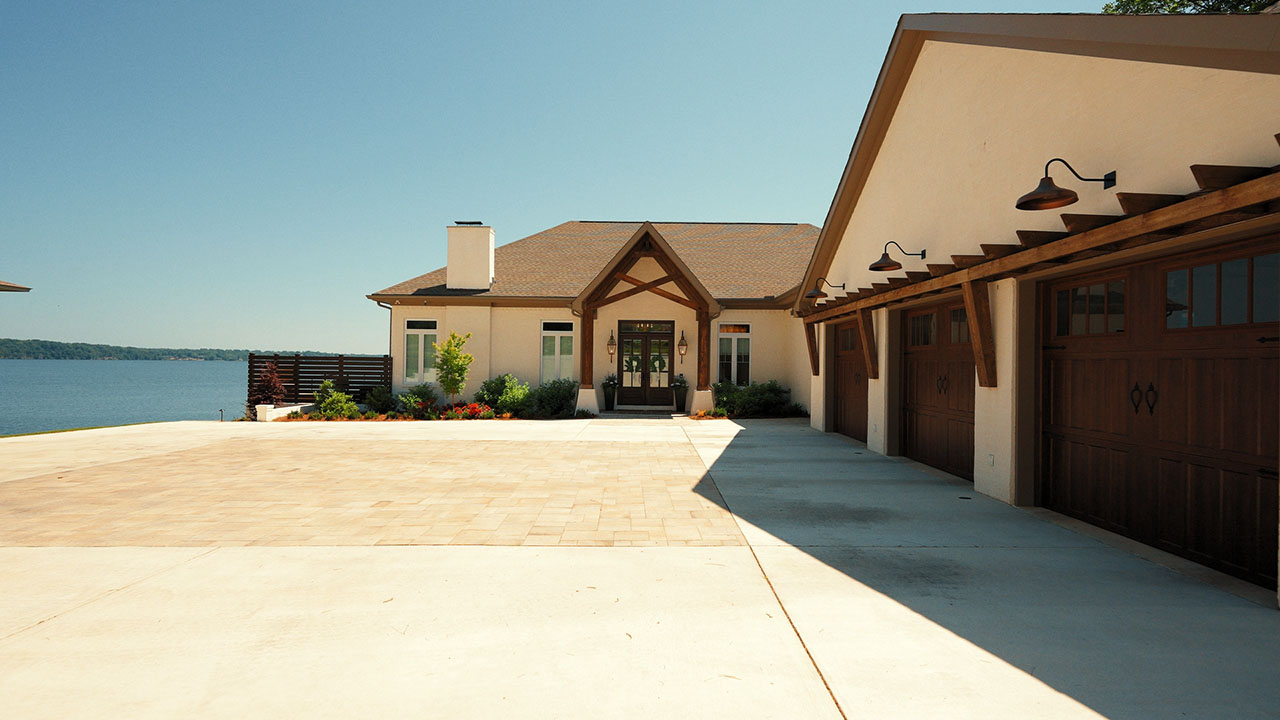 A lakeside Baker Company home with a paver motor court and triple garage